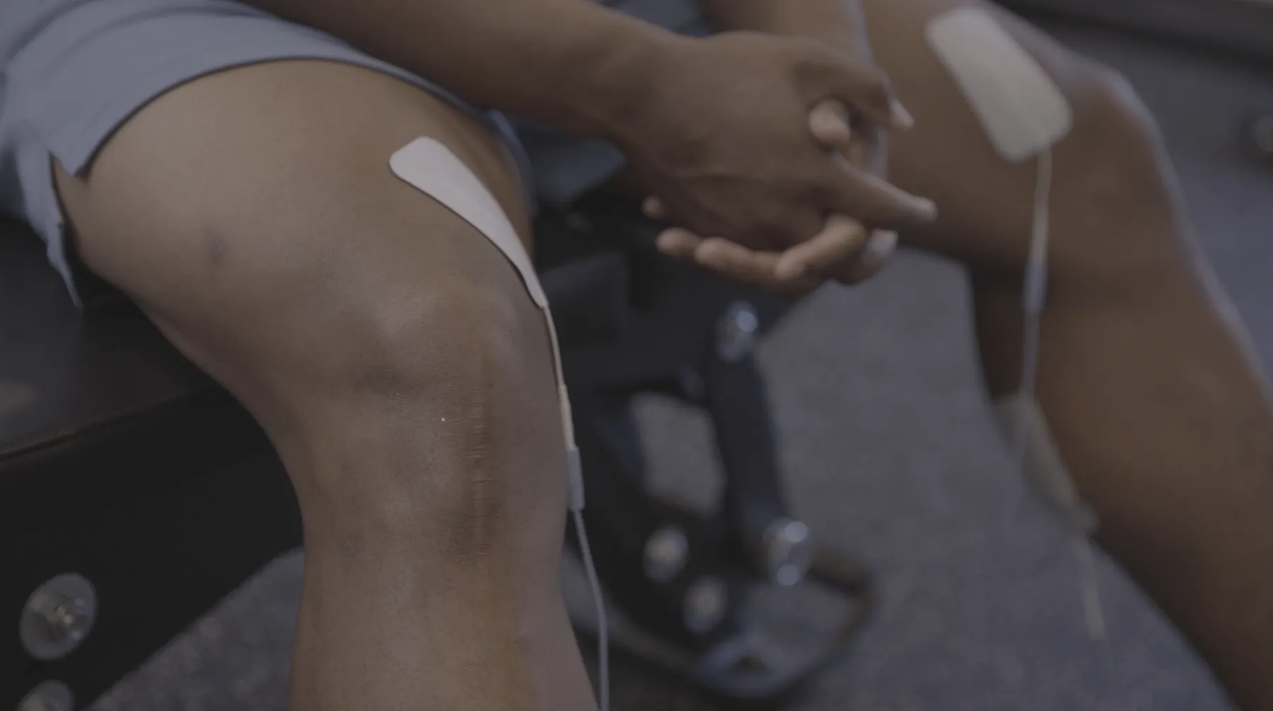Close-up of Saquon Barkley's surgically repaired knee with the ACL surgery scar visible and Volta X electrode pads applied to both legs